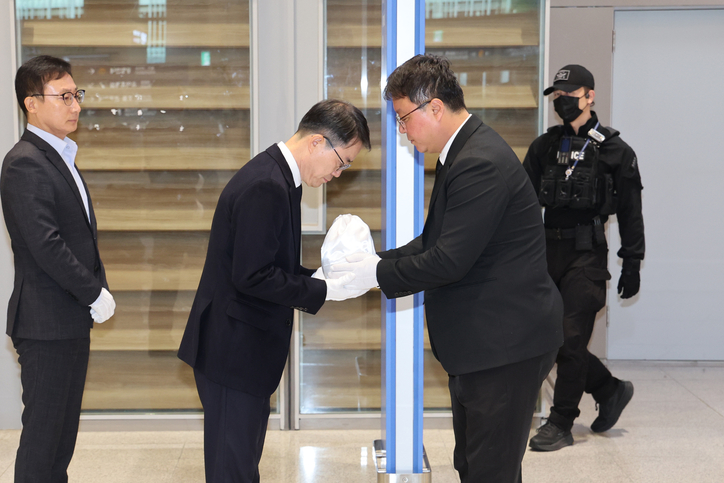 장진욱 경찰청 과학수사운영계장(오른쪽)이 21일 인천국제공항을 통해 캄보디아 범죄 단지에서 고문 후 살해된 20대 대학생 박모(22)씨의 유해를 송환한 뒤 안중만 경북경찰청 형사기동대장에게 인수하고 있다. /연합뉴스